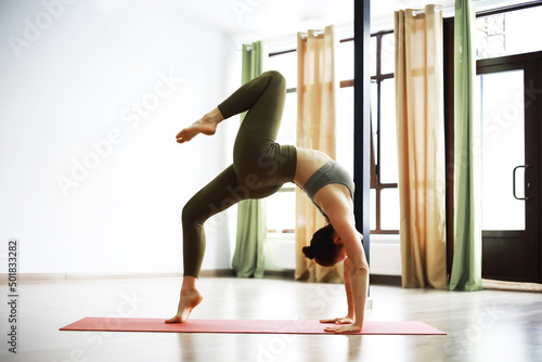 Attractive woman with perfect body in a sports clothes standing in a yoga pose. Concept of sports healthy lifestyle, nutrition and training workout.