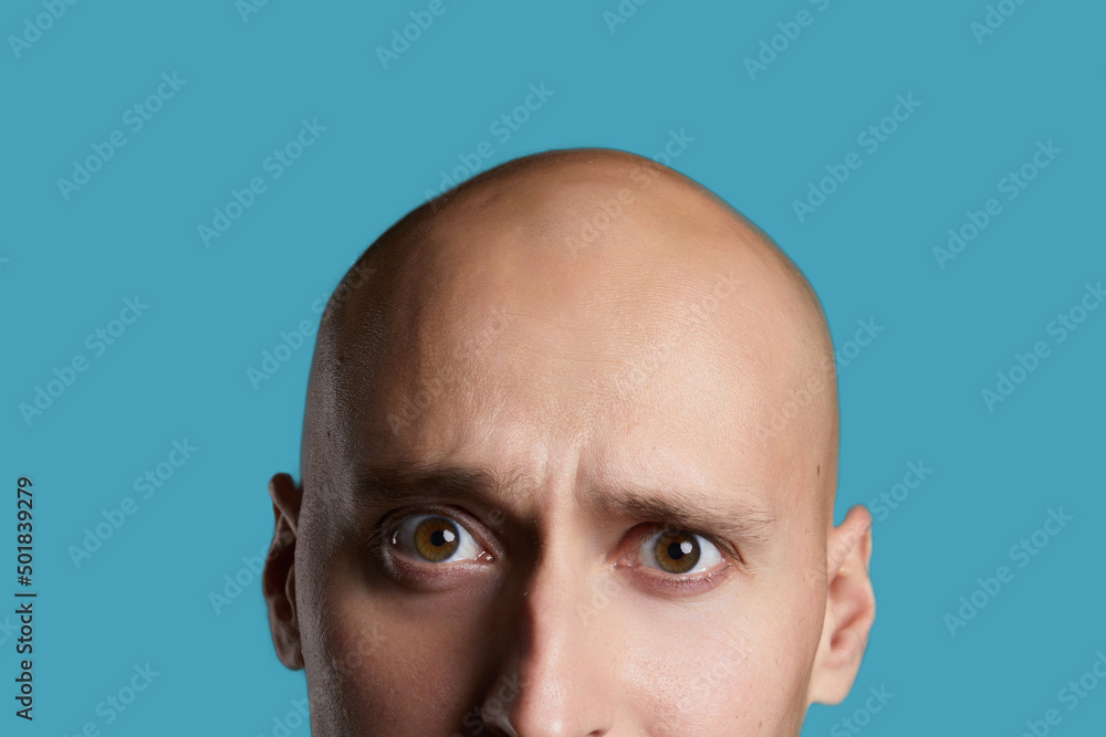 Fototapeta premium bald young guy close-up on an empty blue background