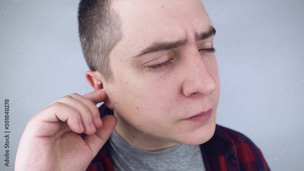 The man puts on earplugs. Close-up of an orange noise barrier. Deep sleep. The ENT doctor advises orange earmuffs to reduce ambient noise. Increased sensitivity to sounds. The man puts on earplugs. Close-up of an orange noise barrier. Deep sleep. The ENT doctor advises orange earmuffs to reduce ambient noise. Increased sensitivity to sounds.
