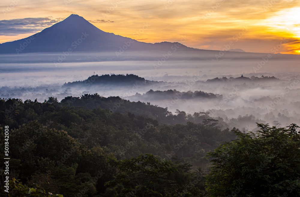 Beautiful Scene of Merapi Merbabu Mountain at Sunrise time from Punthuk Setumbu. In front of the mountain there is silhouette of Borobudur temple. 