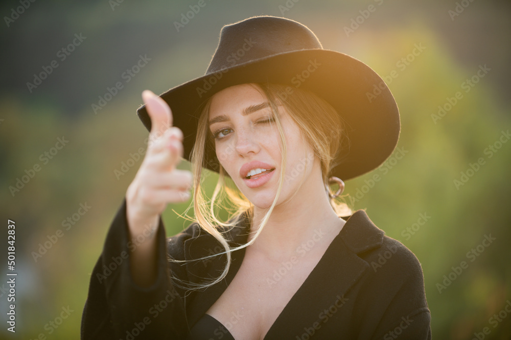 Girl holds hands like a gun. Sensual portrait of elegant young woman outdoors. Beautiful western girl.