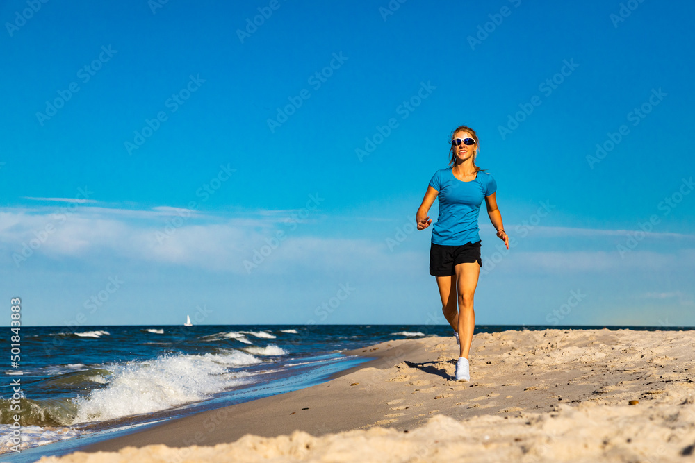 Young woman running, jumping on beach