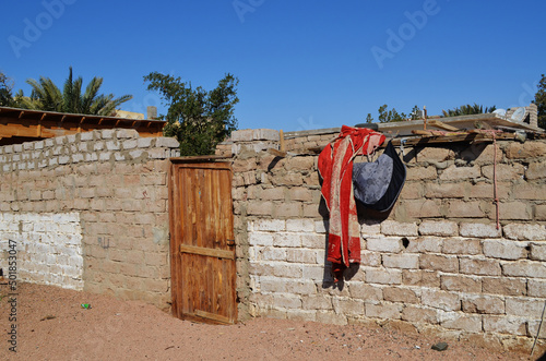 A brick fence with a wooden door. Items are drying. Dahab, Egypt.