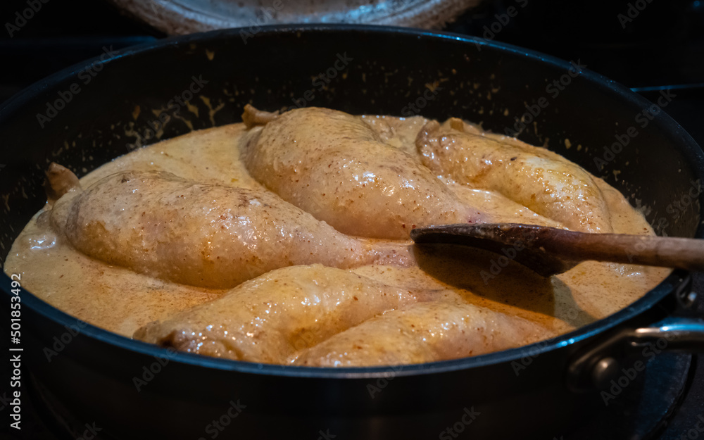 Red thai chicken curry simmering in a pan on a stove Red thai chicken curry simmering in a pan on a stove