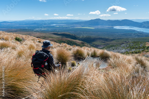 Fototapeta Hiker descending northern slope of Tongariro Alpine Crossing, Lake Rotoaira and Lake Taupo in the distance