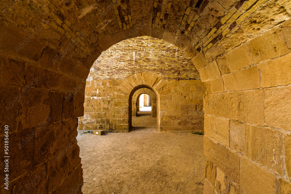 View of stone roman arches linking rooms inside the Maniace Castle in the island of Ortigia, built during the Swabian period by Emperor Frederick II of Swabia.