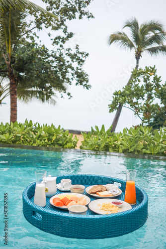Floating breakfast in swimming pool with sea view. Healthy breafast served on the table relaxing in calm pool water  by tropical resort pool  summer beach luxury lifestyle