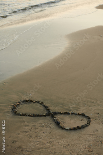 Infinity sign made with small stones on sandy beach