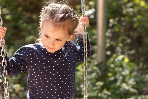 Little beautiful girl smiling swings on a swing in the park