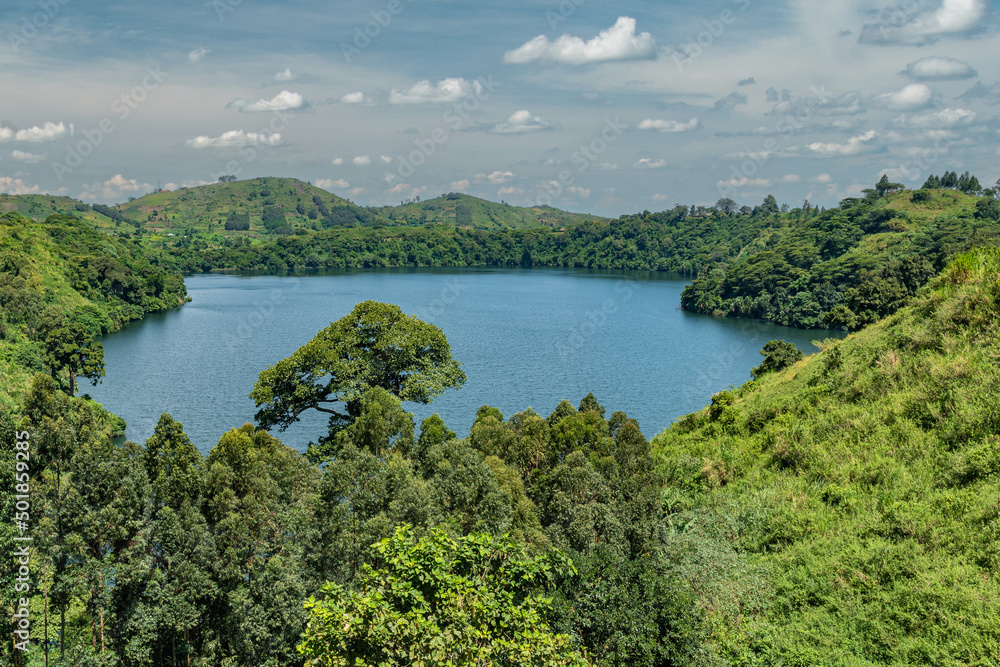 Lush, green landscape surrounding Lake Nyinambuga, an ancient volcanic caldera filled with blue water, part of the crater region in western Uganda, Africa