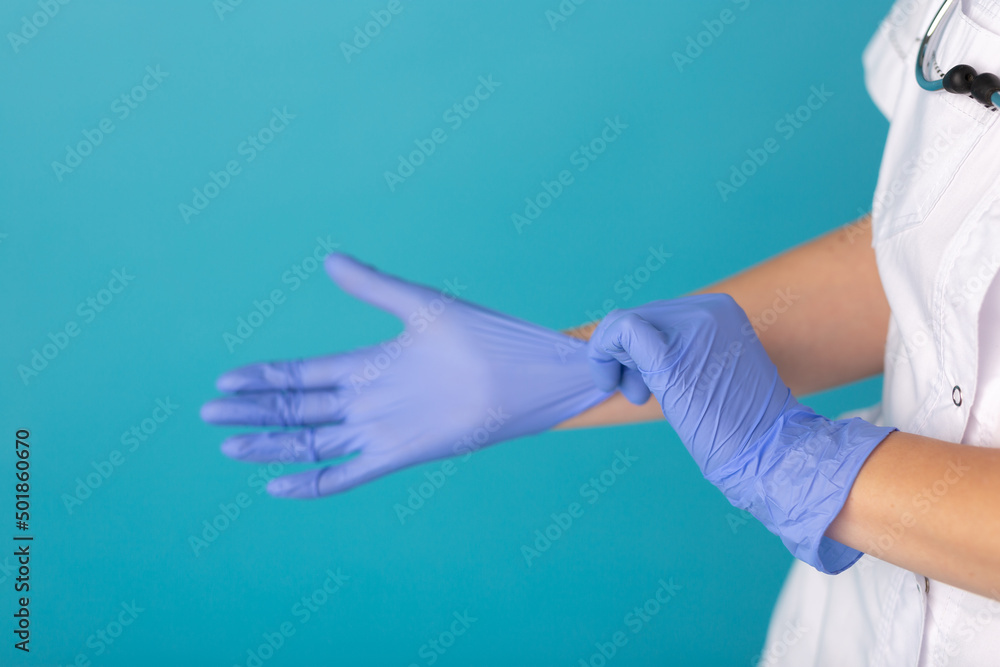 Doctor or nurse in white medical suit puts on protective gloves. Close-up. Concept of professional clinical care, uniform and healthcare Doctor or nurse in white medical suit puts on protective gloves. Close-up. Concept of professional clinical care, uniform and healthcare