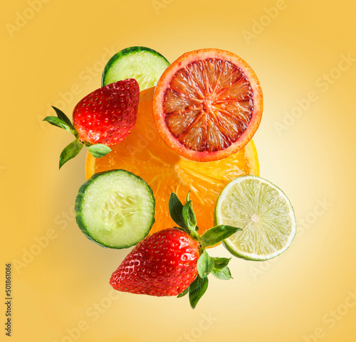 Fototapeta Naklejka Na Ścianę i Meble -  Flying fruits and vegetables group with sliced grapefruit, cucumber, lemon, orange and strawberry levitating on orange background. Healthy refreshing summer food. Front view.
