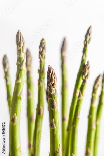 Bunch of green asparagus at white background, close up.  Food background with seasonal spring vegetable ingredients. Front view.