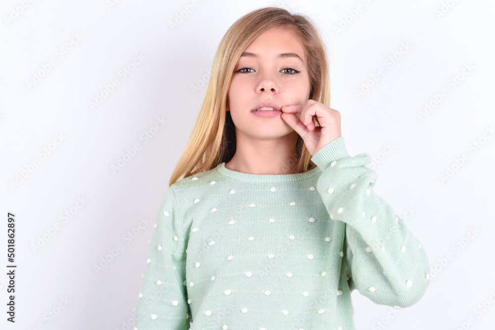 little caucasian kid girl wearing fashion sweater over blue background mouth and lips shut as zip with fingers. Secret and silent, taboo talking. little caucasian kid girl wearing fashion sweater over blue background mouth and lips shut as zip with fingers. Secret and silent, taboo talking.