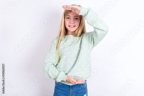 little caucasian kid girl wearing fashion sweater over blue background gesturing with hands showing big and large size sign, measure symbol. Smiling looking at the camera.