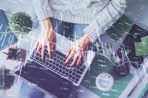 Double exposure of woman hands working on computer and forex chart hologram drawing. Top View. Financial analysis concept.