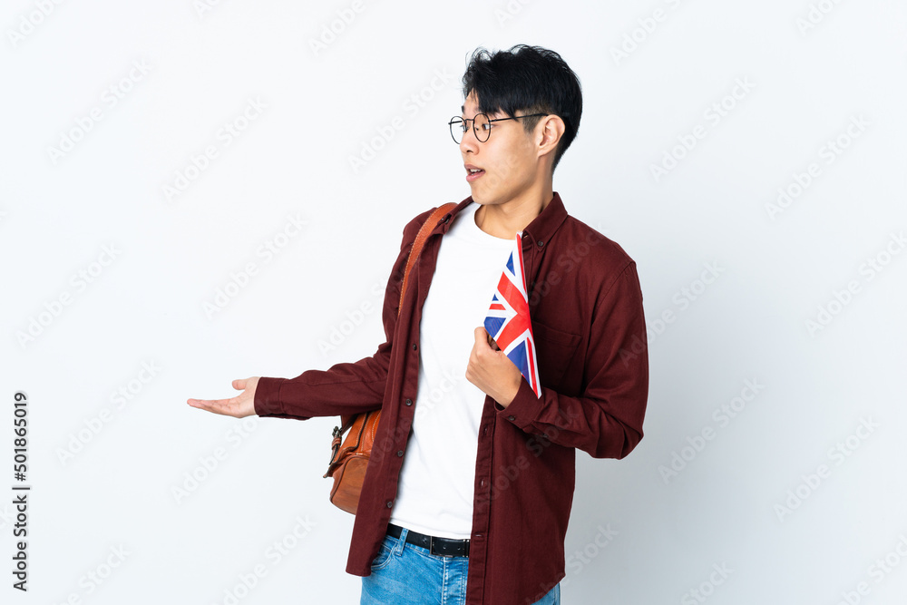 Chinese man holding an UK flag isolated on purple background with surprise expression while looking side Chinese man holding an UK flag isolated on purple background with surprise expression while looking side