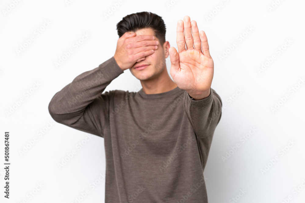 Naklejka premium Young handsome caucasian man isolated on white bakcground making stop gesture and covering face