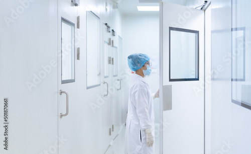 Unidentified microbiologist is open the cleanroom door to enter the room in clean area of microbial laboratory in pharmaceutical factory, concept of science, healthcare and safety operation. photo