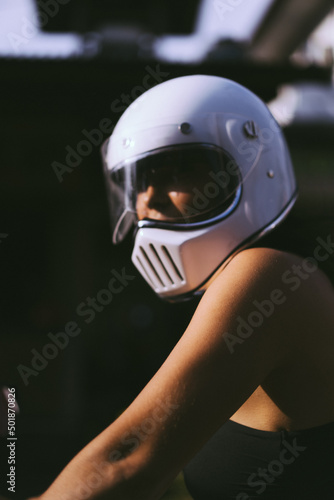 A young woman in a motorcycle full face helmet  rides a motobike. Surfer on a motorcycle, surfboard in racks. Safe driving in Asia. © Yuliya Kirayonak