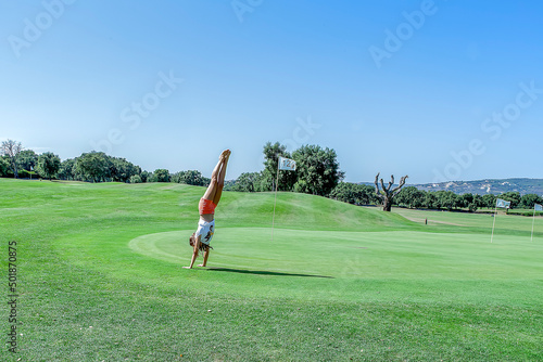 Handstand pirouette executed by a girl next to hole 12 of a golf course