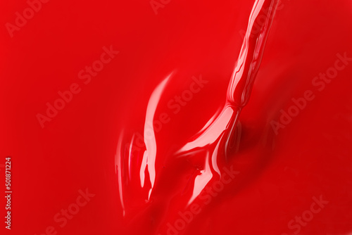 Red nail polish and brush. Nail polish is spilled on the surface. Using nail brush.