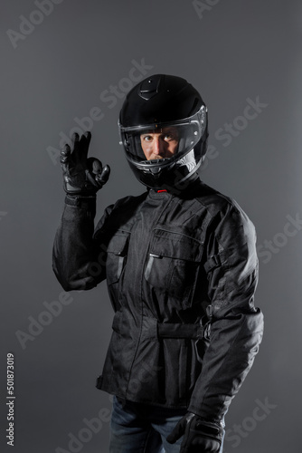 Man wearing protective motor black clothing doing ok sign in studio. © BASILICOSTUDIO STOCK