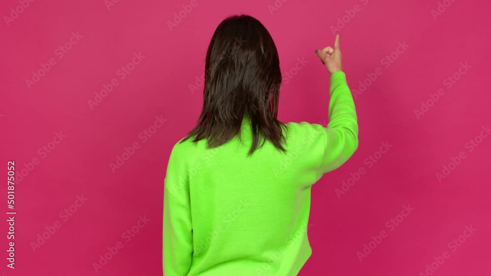 Young brunette woman pointing back with the index finger over isolated background Young brunette woman pointing back with the index finger over isolated background