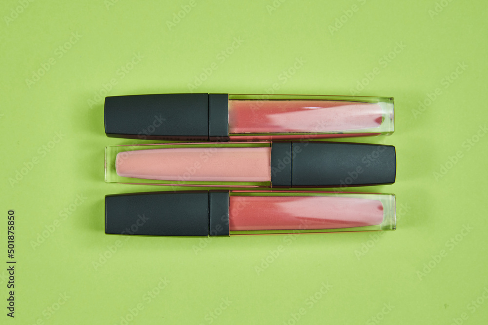 three lipsticks of different colors pattern on a green background isolated three lipsticks of different colors pattern on a green background isolated