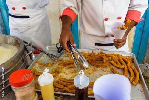 Photography Cuban men with a street cart selling and preparing churros in Havana