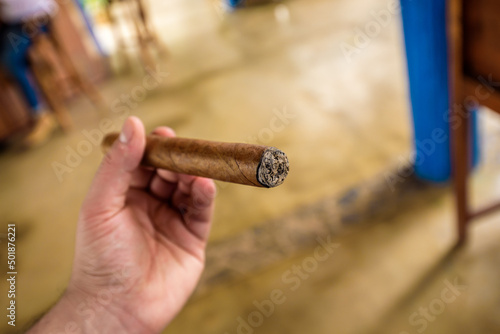 Male hand holding a handmade Cuban laguito cigar with 56 ring gauge photo