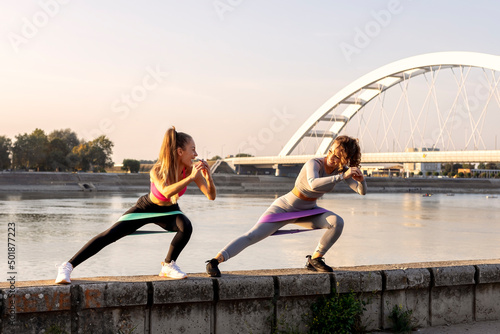 Two woman exercise and stretching outside near the river