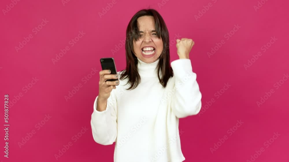 Young brunette woman using mobile phone and celebrating a victory over isolated background