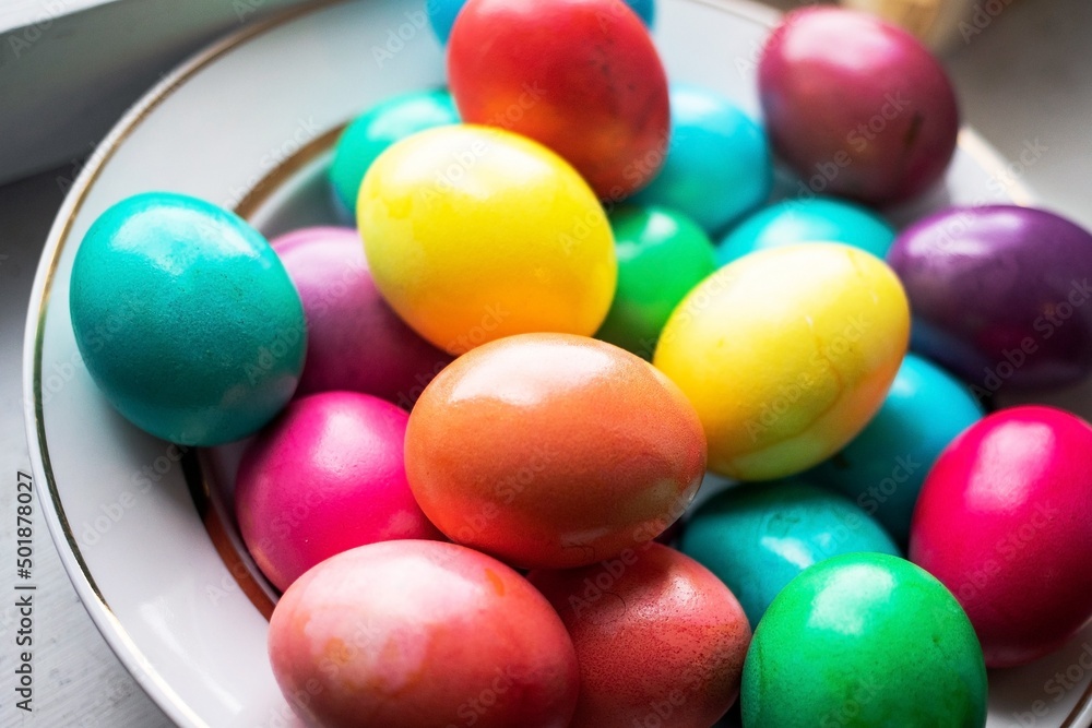 painted multi-colored chicken eggs in a wide white plate as a symbol of the holiday of Catholic believers