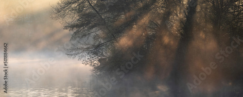 Foto Beautiful landscape image of sunrise mist on urban lake with sun beams streaming