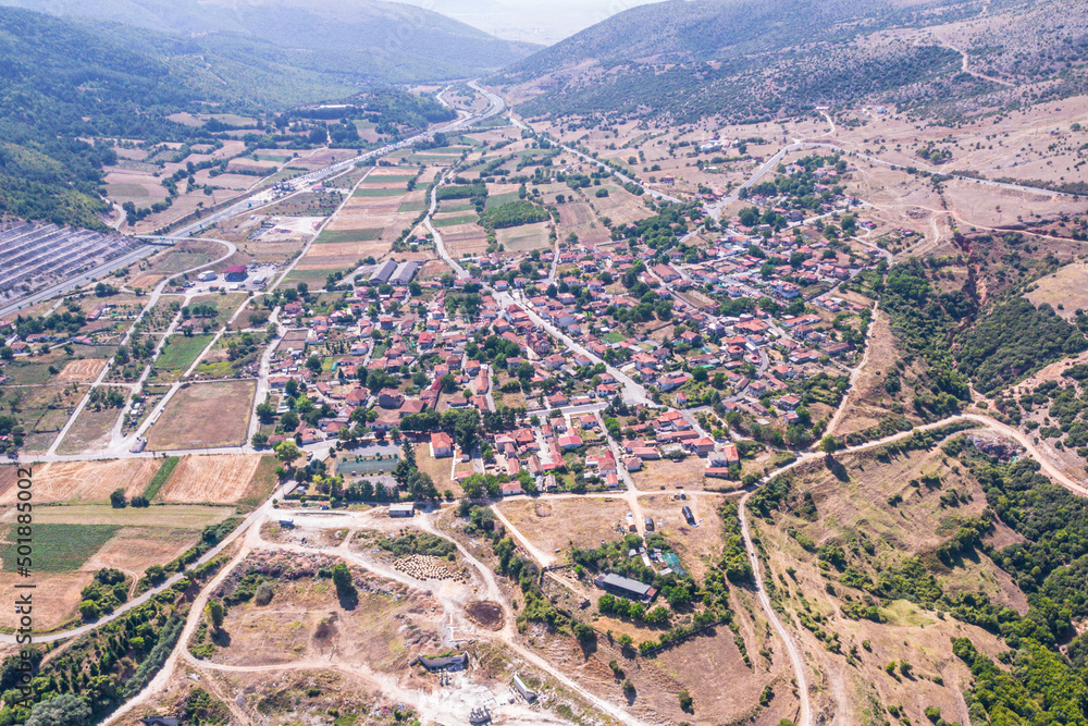Aerial view of traditional village with rural houses, buildings, highway bridge, countryside roads in mountains in Greece. Drone, copter view