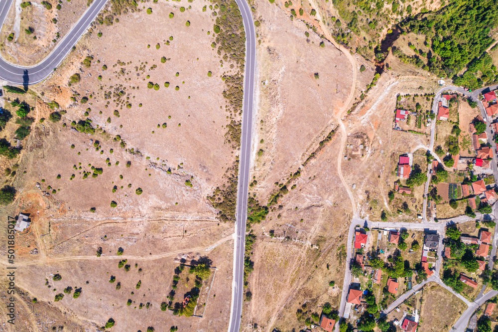 Obraz premium Aerial view of traditional village with rural houses, buildings, highway bridge, countryside roads in Greece. Drone, copter view