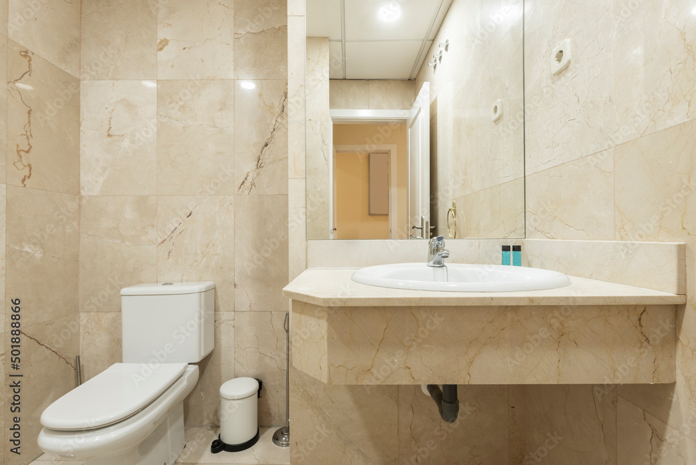 Bathroom with white porcelain sink set in cream marble countertop with built-in frameless mirror Bathroom with white porcelain sink set in cream marble countertop with built-in frameless mirror
