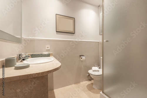 Bathroom with cream marble washbasin to match the floors  framed mirror  plaster border on the wall and shower cubicle with glass partition