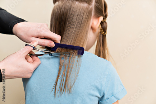 Mom cuts her daughter's wet hair. cutting hair at home. life hacks and rules of hair care. special combs and scissors for hairdressers.