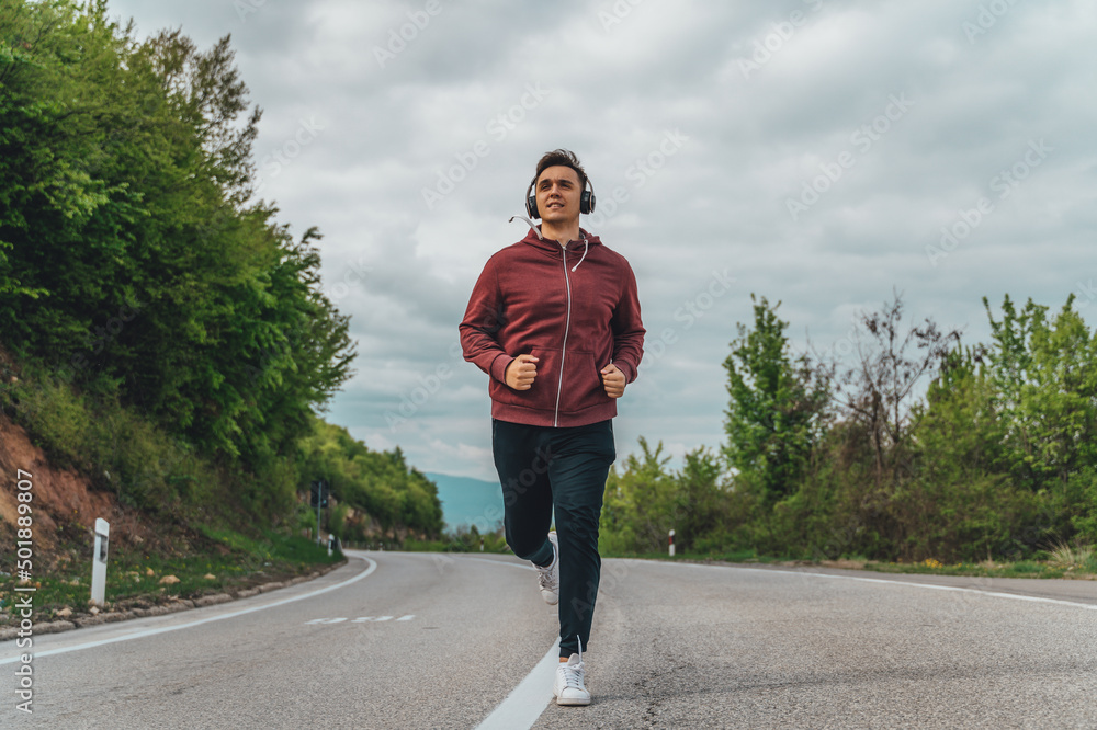 A man is running uphill on the road outside during the day A man is running uphill on the road outside during the day