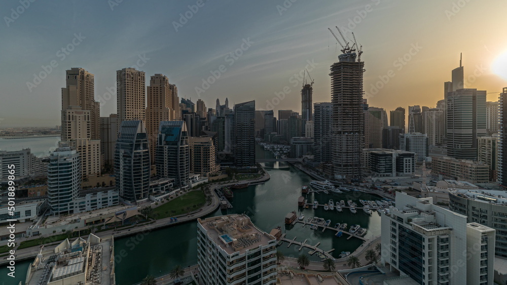 Obraz premium Panorama showing Dubai Marina with several boats and yachts parked in harbor and skyscrapers around canal aerial morning timelapse.