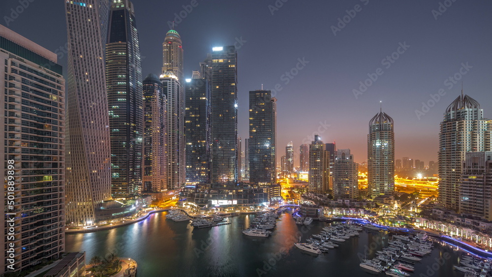 Fototapeta premium Dubai marina tallest skyscrapers and yachts in harbor aerial night to day timelapse.