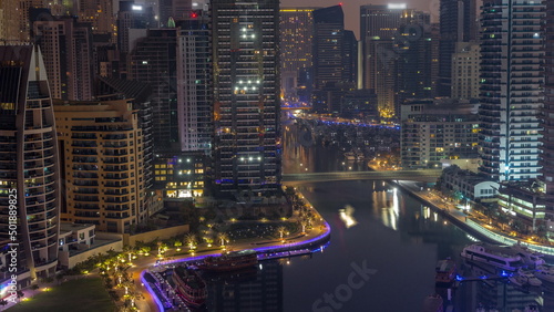 Dubai Marina with several boats and yachts parked in harbor and skyscrapers around canal aerial night to day timelapse. © neiezhmakov