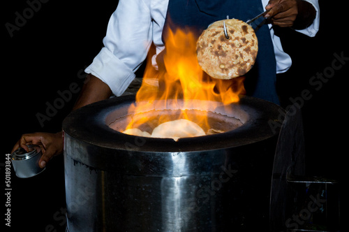 Chef make Naan bread in front of the tandoori oven