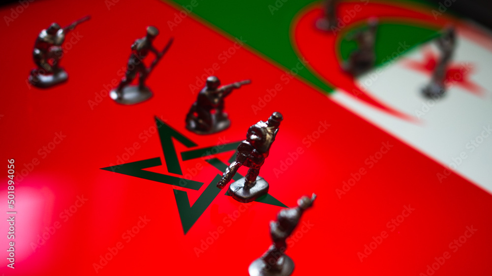 The concept of the economic and political crisis between Morocco and Algeria, toy soldiers attacking each other against the background of national flags.
