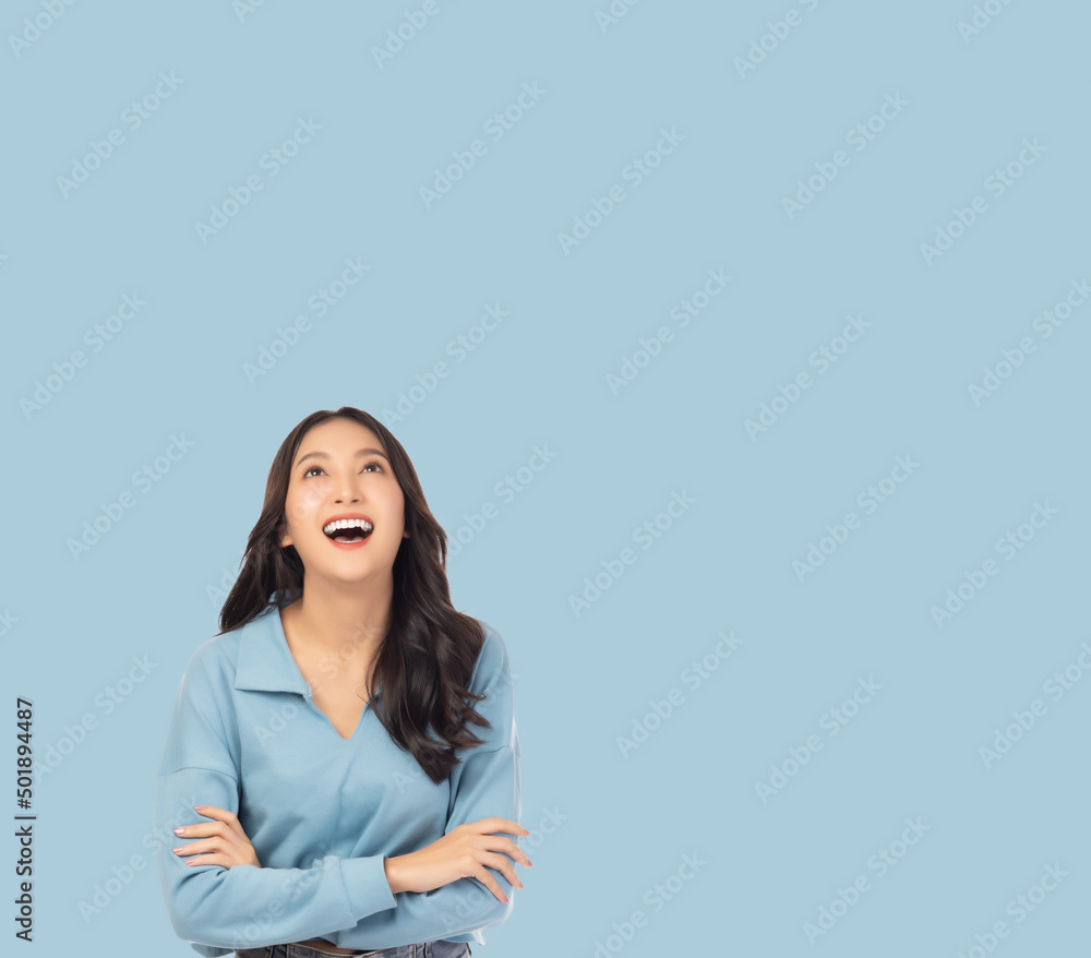Portrait smiling young asian woman with crossed arms Happy asia girl posing with crossed arms and looking at above stand over light blue background and copy space Confident female get happy and relax Portrait smiling young asian woman with crossed arms Happy asia girl posing with crossed arms and looking at above stand over light blue background and copy space Confident female get happy and relax