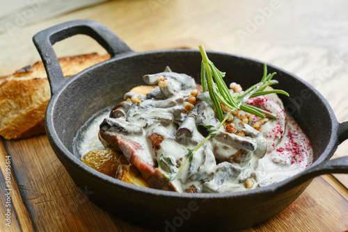 Frying pan with baked potatoes with mushrooms and steak with sauce. Shallow depth of field