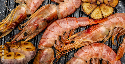 Grilled tiger shrimps with spice, lemon and garlic in a frying pan on a dark background. Prawns fried on a dark background, Seafood appetizer, Culinary, cooking concept, top view