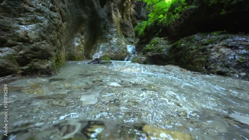 Jungle. Nature. Cold water from mountain moves between cliff in forest. Stream of pure water from low andle. Waterfall. photo
